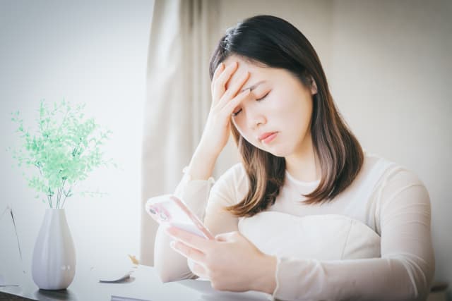 スマホを持って悩む女性